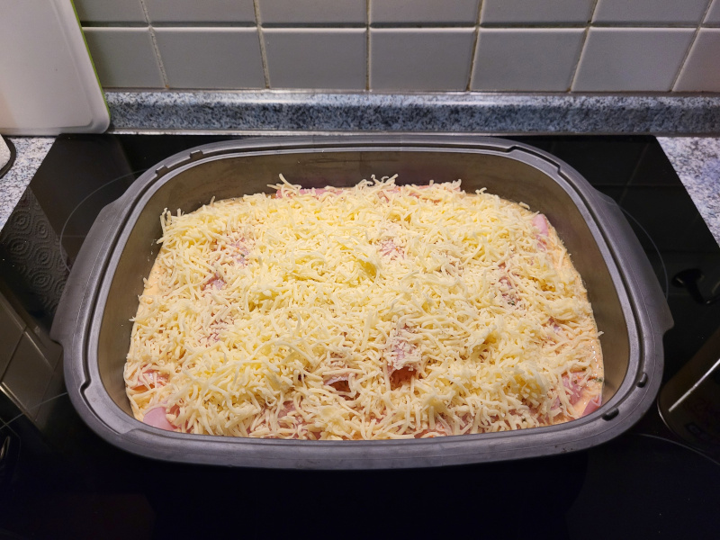 Auflaufform gefüllte mit Röllchen, Soße und Reibekäse